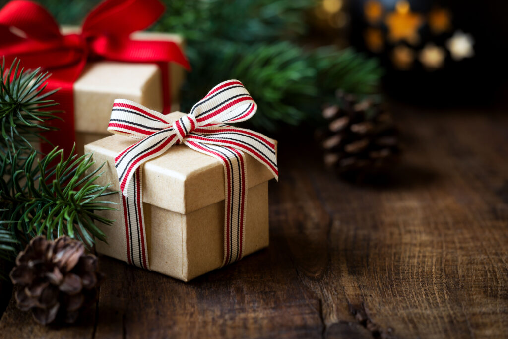 Wrapped Christmas gifts on dark rustic wooden table with pine co - Tradeinfo.cz