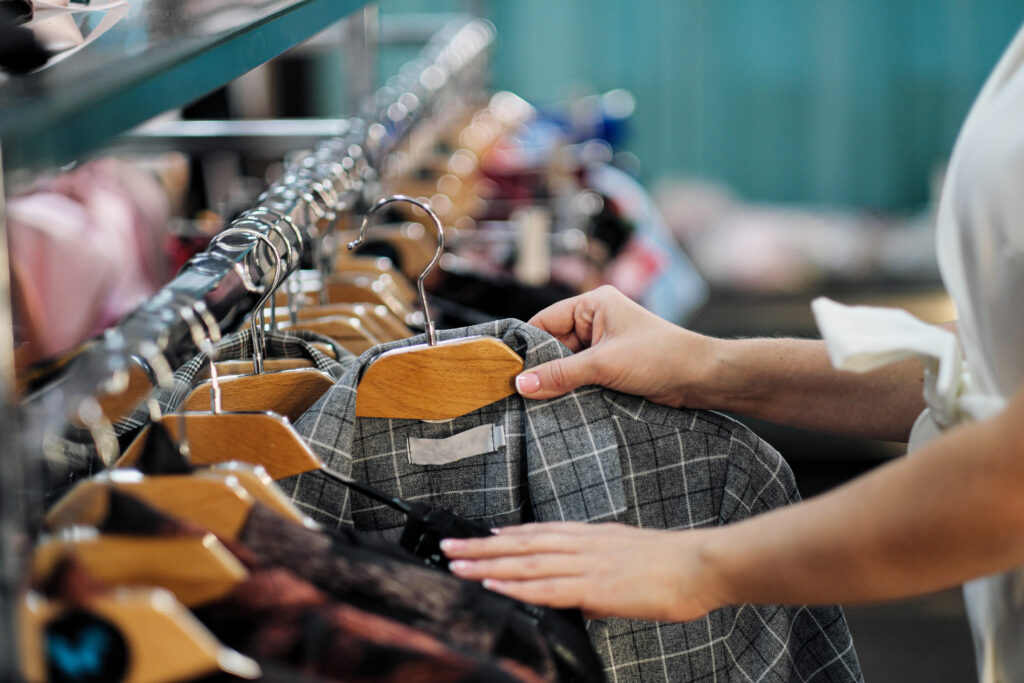 Close-up of the hands of a woman choosing clothes on a hanger in a store - Tradeinfo.cz 2026