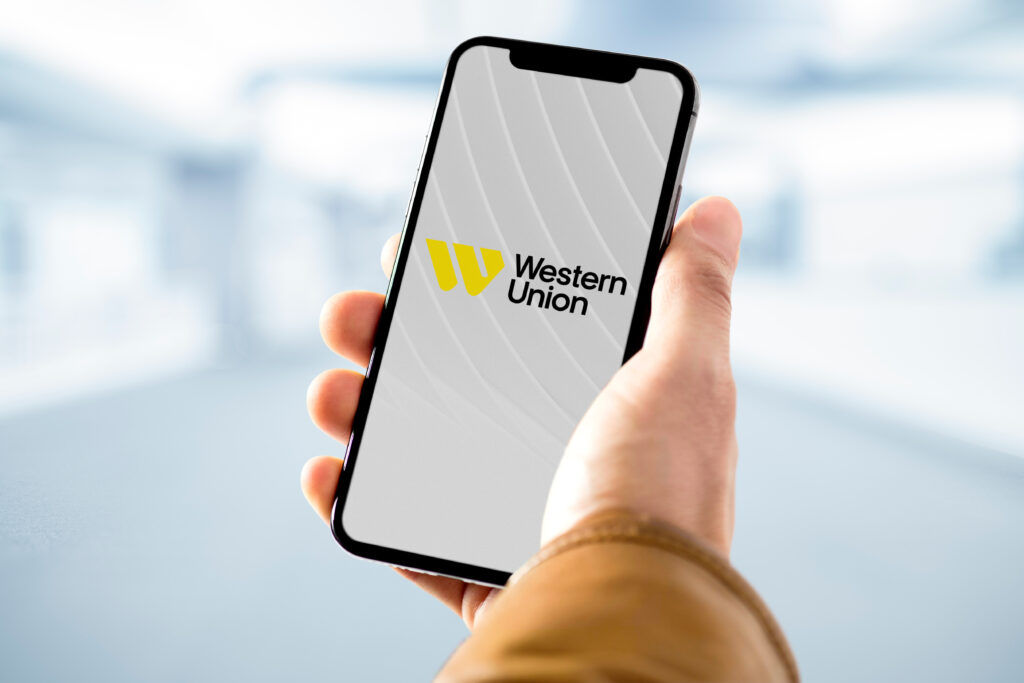 Businessman holding smartphone with western union logo on screen - Tradeinfo.cz Western Union, digitální převody, kryptoměny