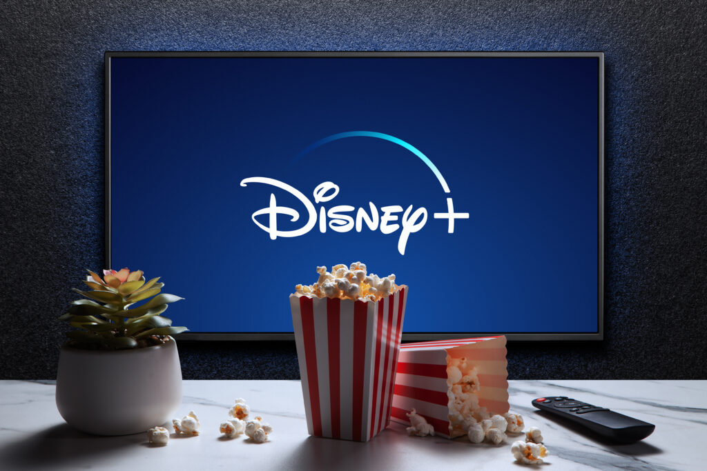 Disney plus logo on TV with popcorn boxes reomote control and home plant Astana Kazakhstan - July 21 2023 - Tradeinfo.cz Disney+, zisky