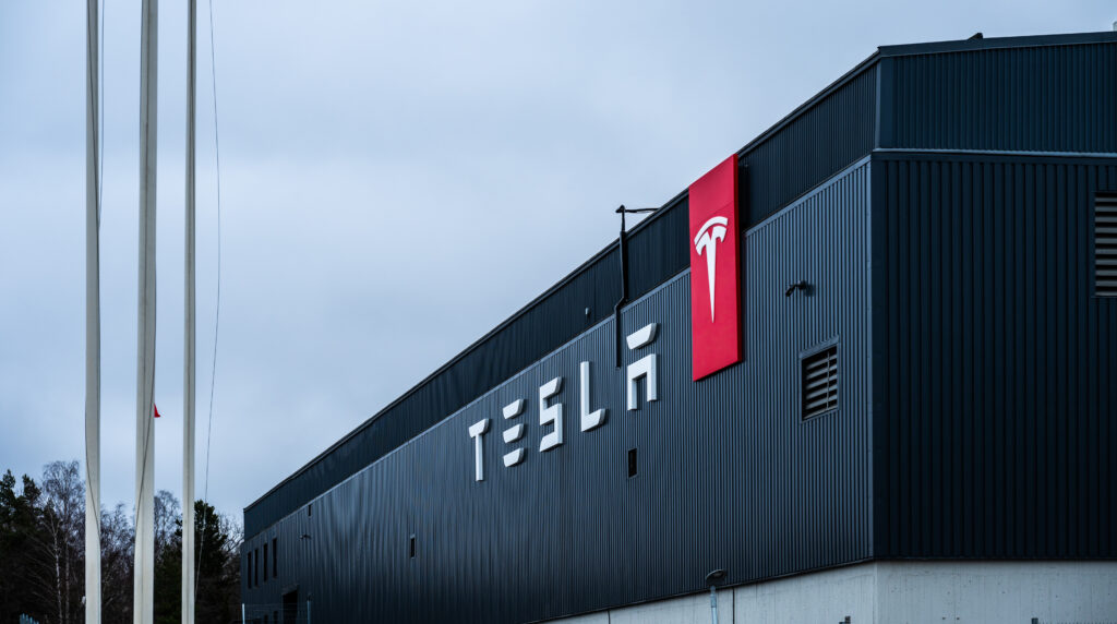 Stockholm Sweden - March 09 2024 tesla manufacturing facility exterior with logo and flagpoles - Tradeinfo.cz Tesla: automobilka, AI, robotaxi