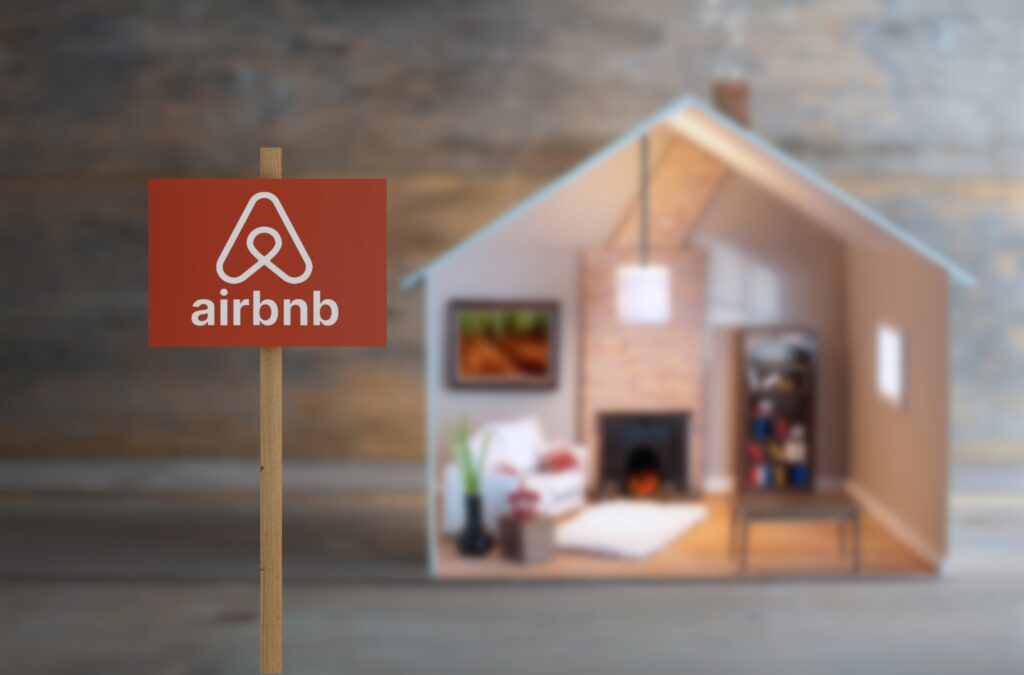Airbnb sign next to a model house with lights on inside - Tradeinfo.cz Airbnb