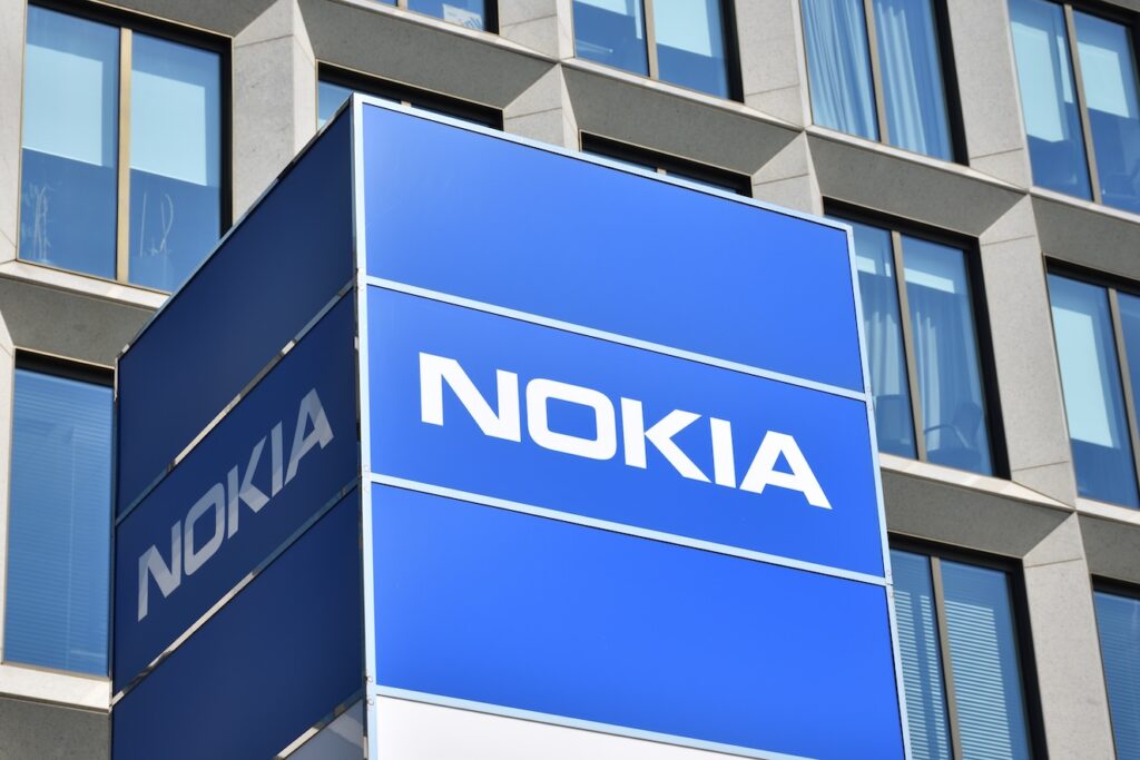 Nokia - Tradeinfo.cz Blue Nokia sign on the side of a modern office building with glass windows behind it, logo clearly visible.