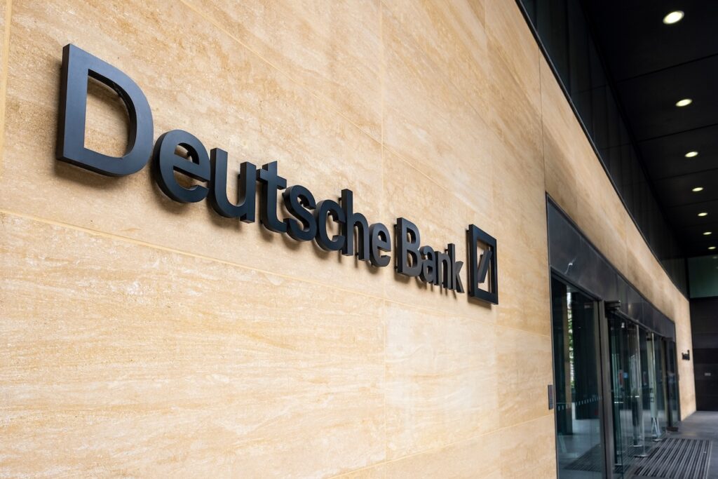 Deutsche Bank - Tradeinfo.cz Deutsche Bank sign mounted on a beige stone wall of a modern building exterior.