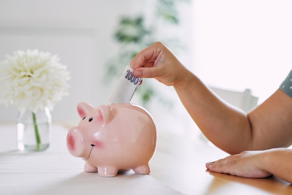 A woman puts a thousand crowns note in the piggy bank - Tradeinfo.cz tisíc korun